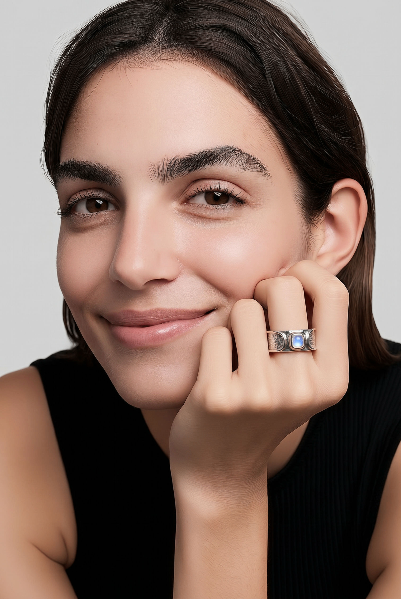 Model resting hand on cheek wearing the Signature Nose-Print Ring with moonstone
